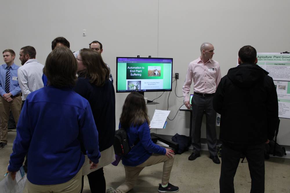 people standing around a senior project on a tv